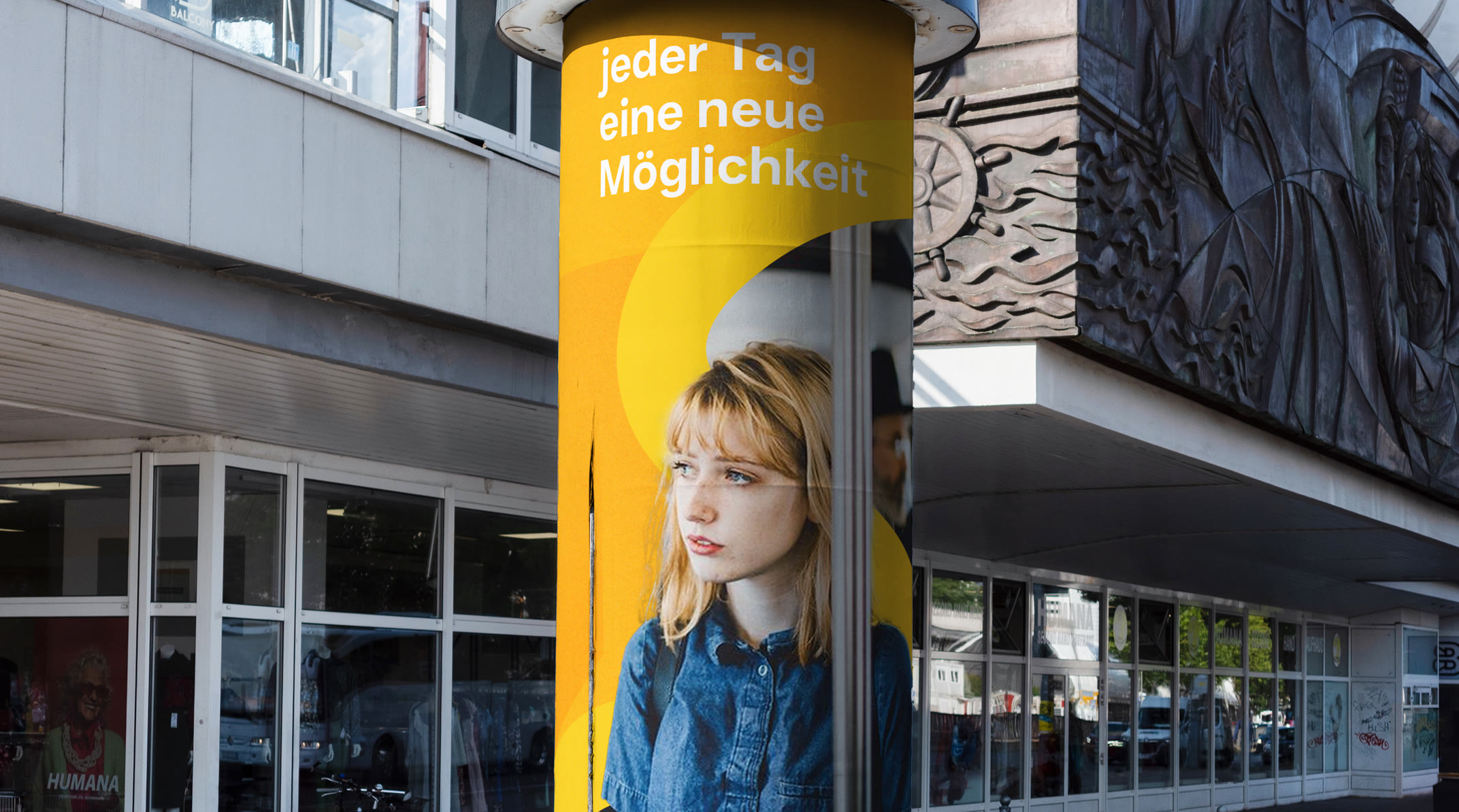 Yellow advertising column on a pavement, carrying the line Jeder Tag eine neue Möglichkeit, every day a new possibility, with a photograph of a young woman filling the lower half
